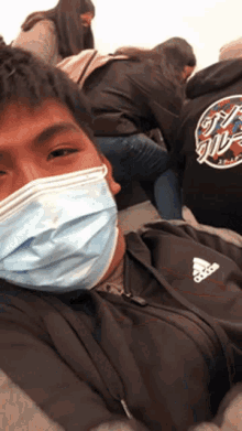 a man wearing a face mask and an adidas hoodie