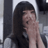 a woman covering her mouth with her hands while smiling
