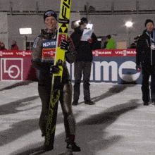 a woman is holding a pair of skis with the name nami on her shirt