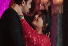 a man and a woman are dancing together in a room . the woman is wearing a red dress .