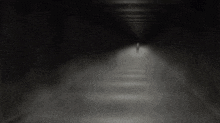 a person in a white shirt is standing in a dark room