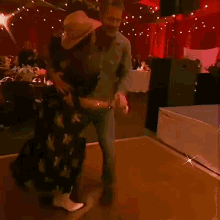 a man is carrying a woman on his shoulders while they dance on a dance floor