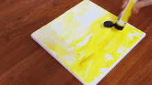 a person holding a tube of yellow paint on a canvas