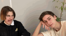 two young men are sitting next to each other and one of them is wearing a black hoodie with the letter f on it