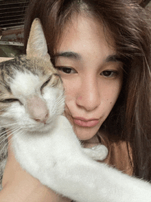 a woman holds a cat in her arms and the cat is sleeping