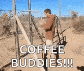 a man is standing next to a fence with the words `` coffee buddies '' written on the ground .