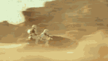 two storm trooper figures are running through a sandy desert