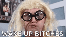 a man wearing glasses and a blonde wig is making a funny face and says wake up bitches
