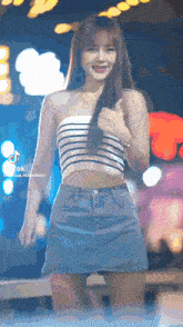 a woman wearing a striped top and a denim skirt is dancing