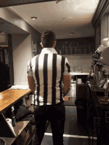 a man in a black and white striped shirt standing in a kitchen