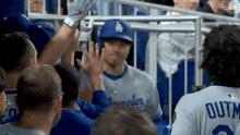 a baseball player is being high fived by his teammates in the stands .
