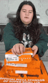 a woman is putting a box of pizza on top of a box that says official pizza sponsor of super bowl lii