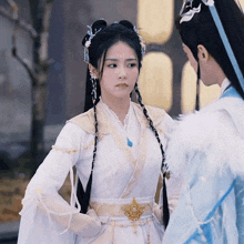 a woman in a white and gold dress stands next to a man in a blue and white outfit