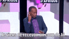 a man in a suit is sitting at a table with the words je viens de recevoir un coup de fil written below him