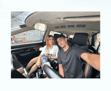 a man and a woman are sitting in the back seat of a car taking a selfie