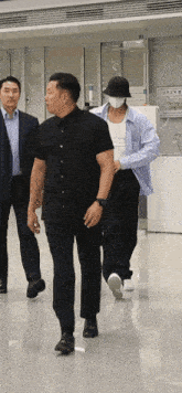 a man wearing a mask and a hat is walking with two other men
