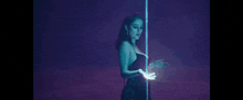 a woman is standing next to a pole in a dark room holding a light .