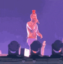 a man singing into a microphone with a cup on his head
