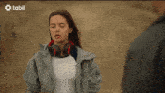 a woman wearing headphones is standing next to a man with tabii written on the bottom