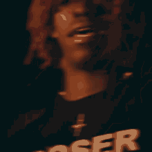 a blurry picture of a man with red hair wearing a shirt that says loser .