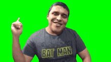 a man wearing a batman t-shirt is pointing at the camera