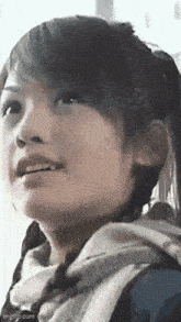 a close up of a woman 's face with a ponytail and a sweater .