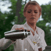 a woman in a white striped suit is pouring a drink into a martini glass