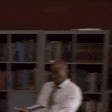 a blurry picture of a group of men in suits and ties sitting in front of a bookshelf .