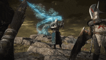 a man in a knight 's armor stands on a rock with a sword