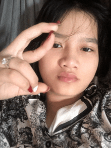 a woman with a ring on her finger holds her eyebrow