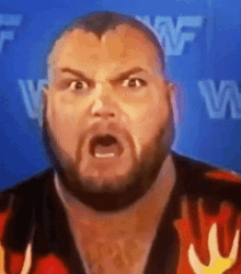 a man with a beard is making a funny face in front of a blue wall with the letter w on it