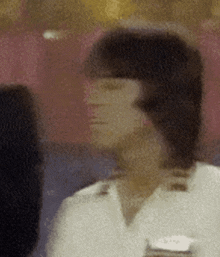 a blurred image of a person 's face with a name tag on their chest