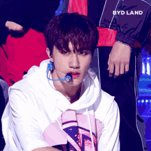 a boy in a white hoodie with a microphone in his mouth and the word byd land behind him