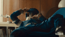 a man in a space suit is laying on a chair with the fantastic 4 logo on the bottom