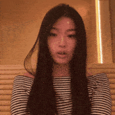 a woman with long hair is wearing a black and white striped top