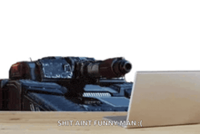 a laptop sits on a desk next to a tank that says " shit aint funny man "