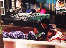 a man and woman laying on a couch in a bedroom
