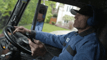 a man wearing headphones is driving a truck with the word mail on his uniform