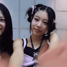 a woman wearing a necklace with a spider on it is standing next to another woman