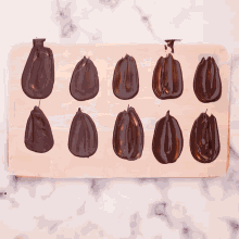 a person 's hand is reaching for a piece of chocolate on a wooden tray