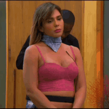 a woman wearing a pink top and a bandana around her neck stands in front of a microphone .