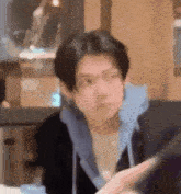 a young man is sitting at a table in a restaurant looking at a tablet .