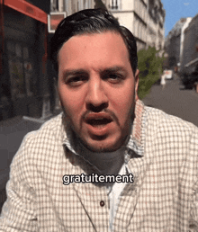 a man wearing a plaid shirt has the word gratuitement on his face