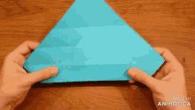 a person is holding a piece of blue paper that is folded into a triangle ..