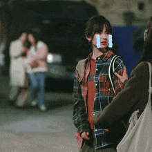 a girl in a plaid shirt has a blue sticker on her face