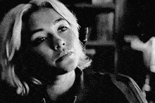 a black and white photo of a woman looking at the camera with a serious look on her face .