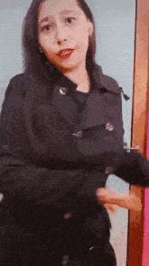 a woman in a black coat is standing in front of a door .