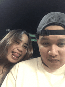 a man and a woman are posing for a picture and the man is wearing a gray hat
