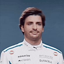 a man is wearing a white racing suit with sponsors such as komatsu and duracell