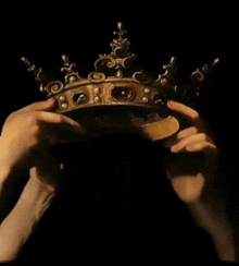 a close up of a person holding a crown with a black background